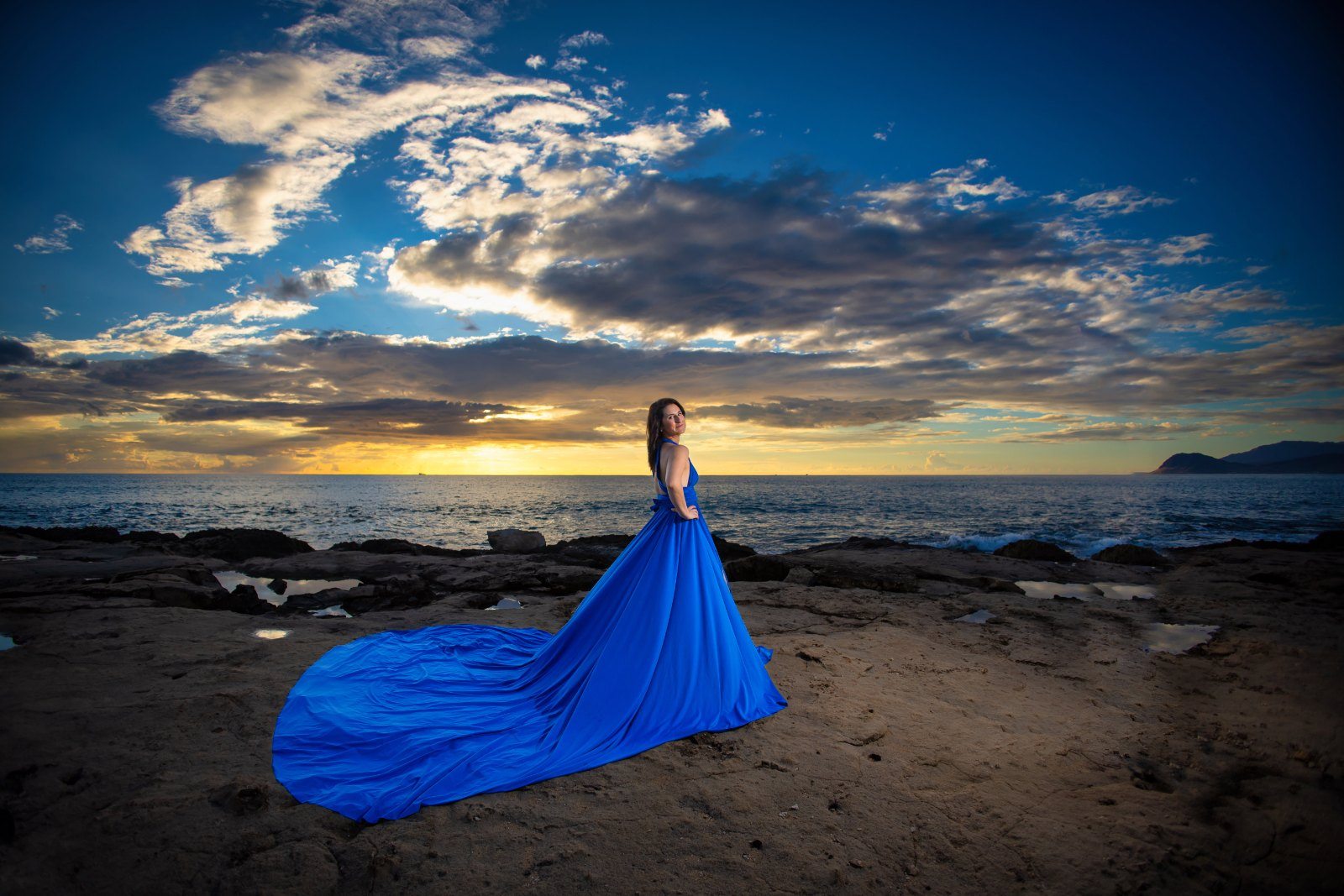 Flying dress photography, blue gown train sweeping across the shoreline rock at sunset, Oahu