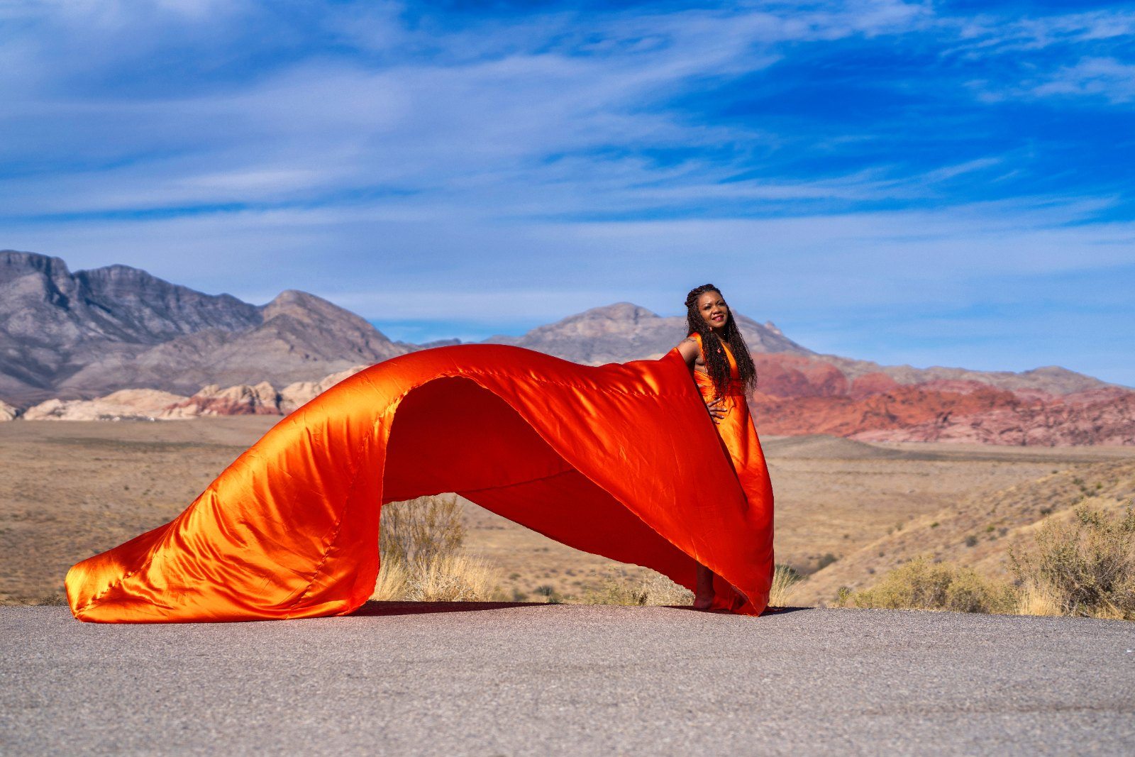 Flying dress photography, orange gown arcing over the desert road at Red Rock, Las Vegas