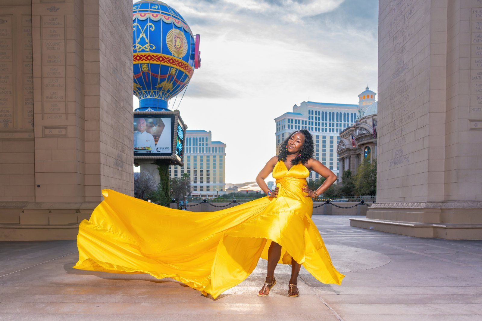 Flying dress photography, yellow gown spread wide under the Paris arch on the Las Vegas Strip